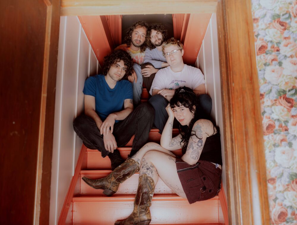 Wednesday the band, sat on a staircase, looking towards the camera.